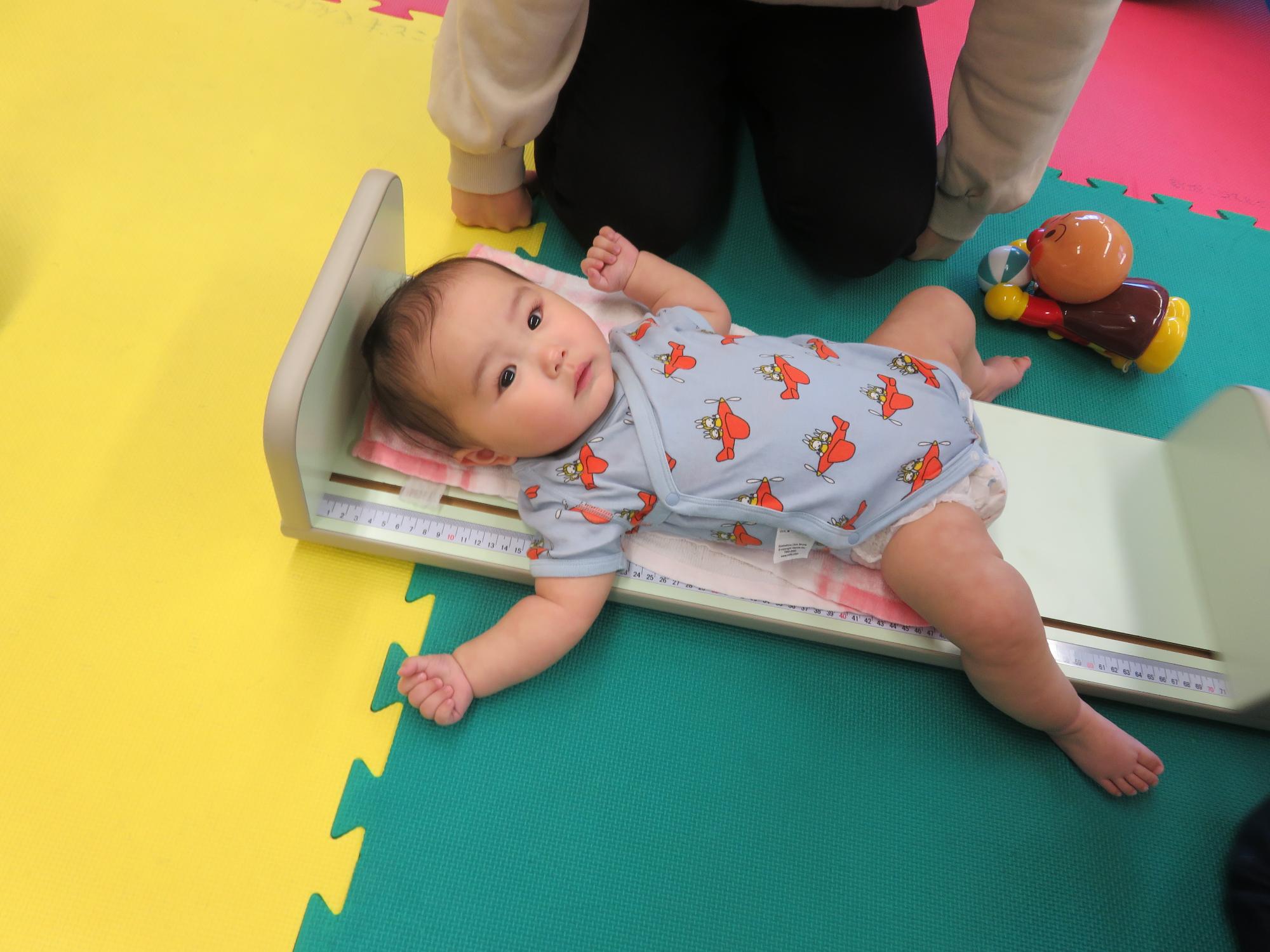 リラックスした表情で身長を測る乳児