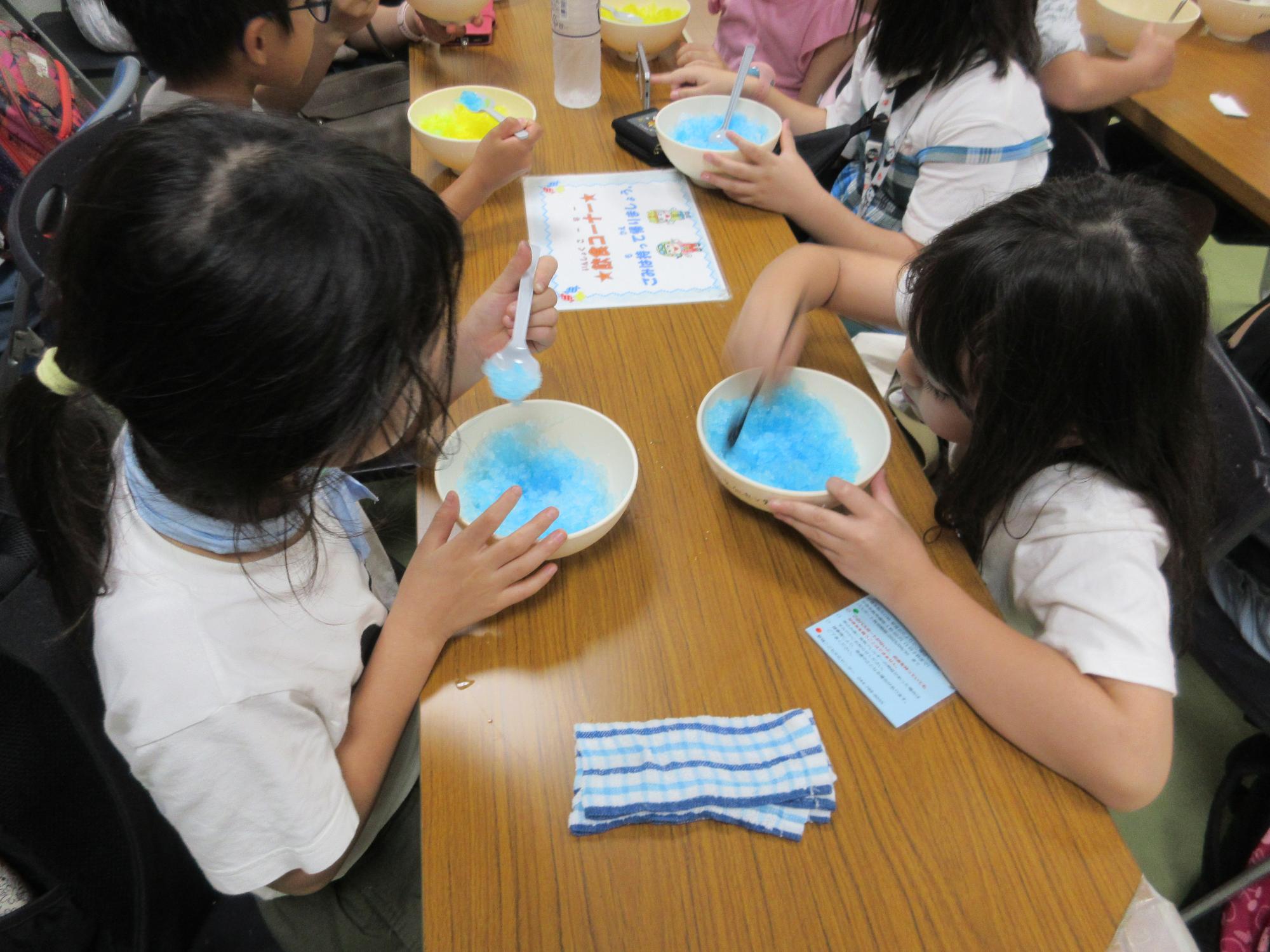 ブルーハワイの涼し気なかき氷を食べる子どもたち