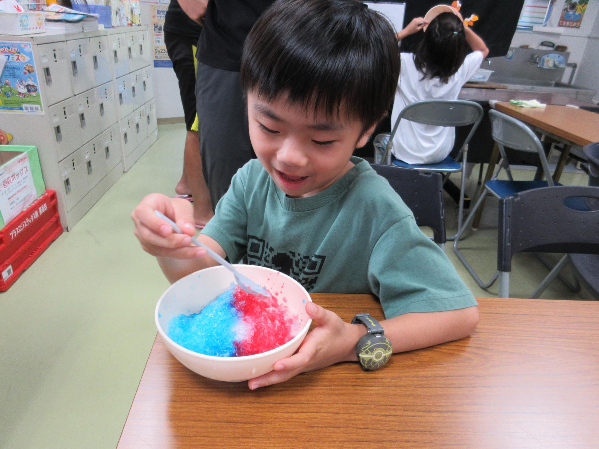 ブルーハワイといちごのミックス味のかき氷を食べる子ども