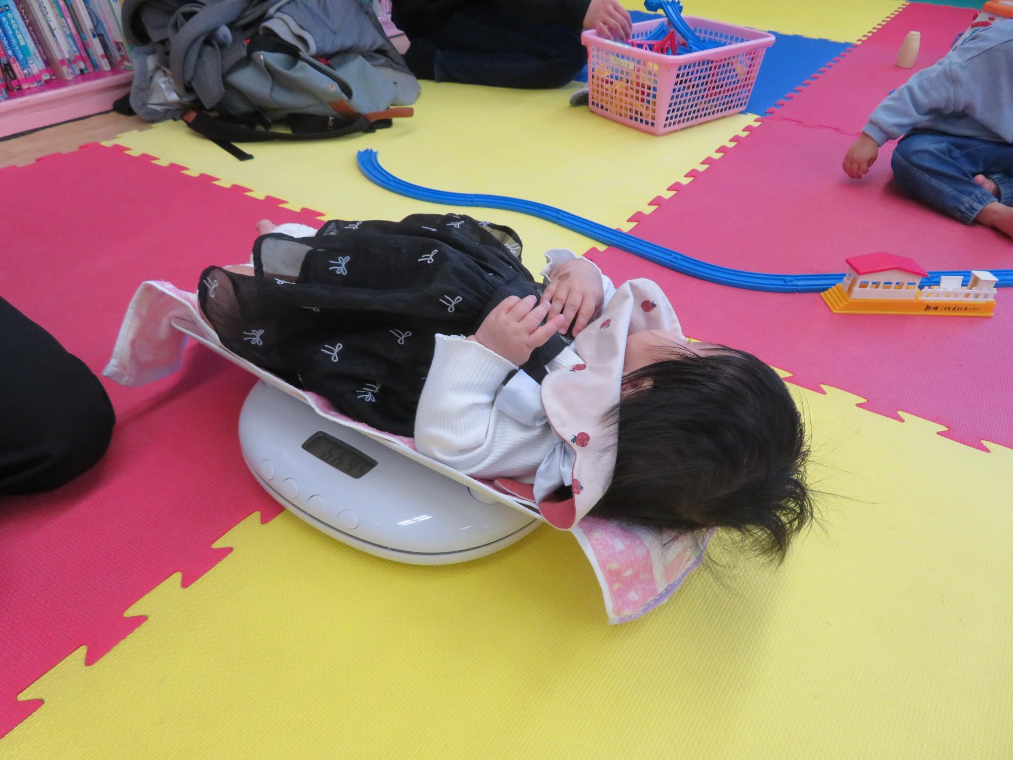 プラレールを眺めながら体重を測るこども