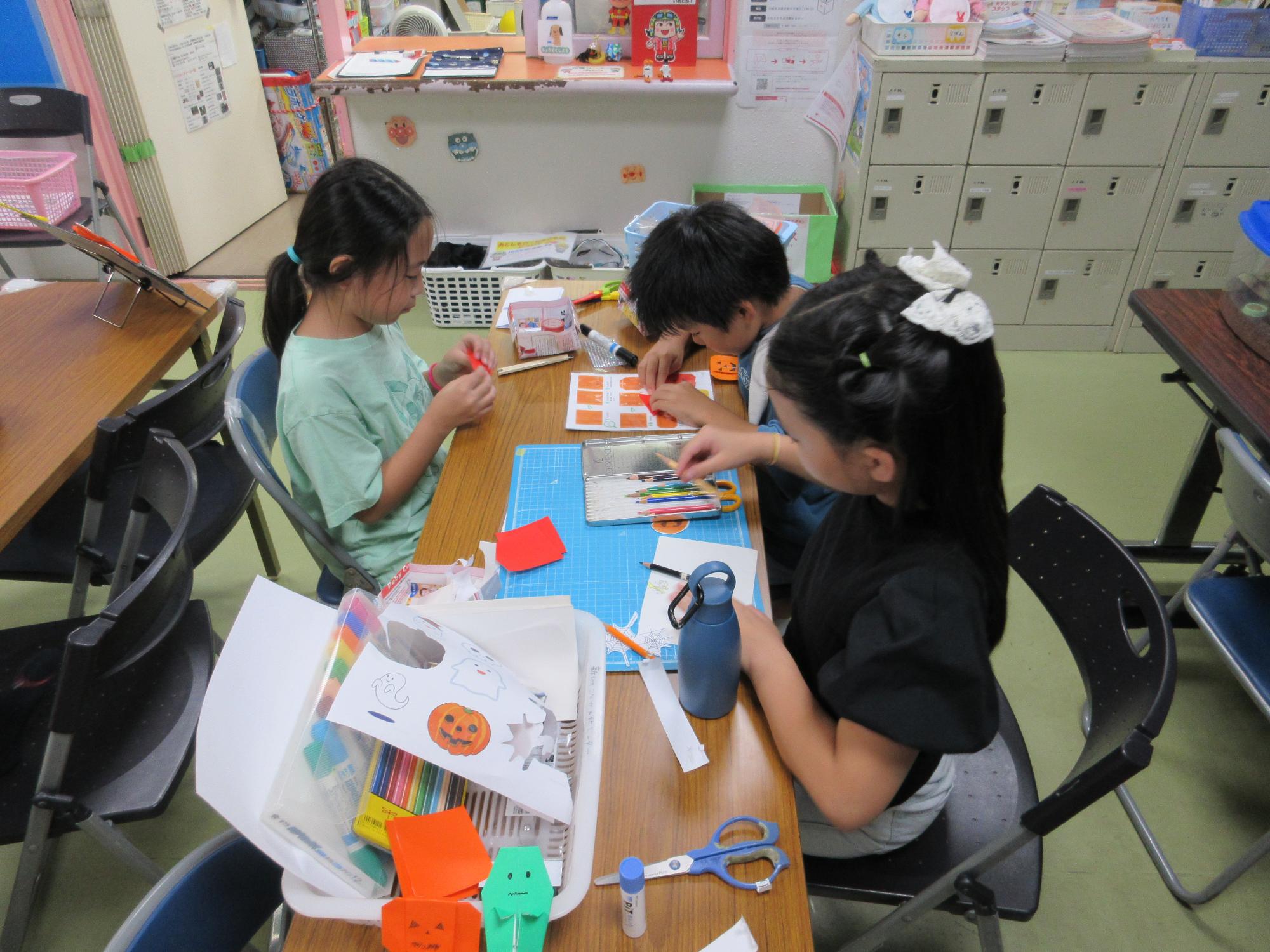 折紙でハロウィンのかぼちゃを折る子どもたち