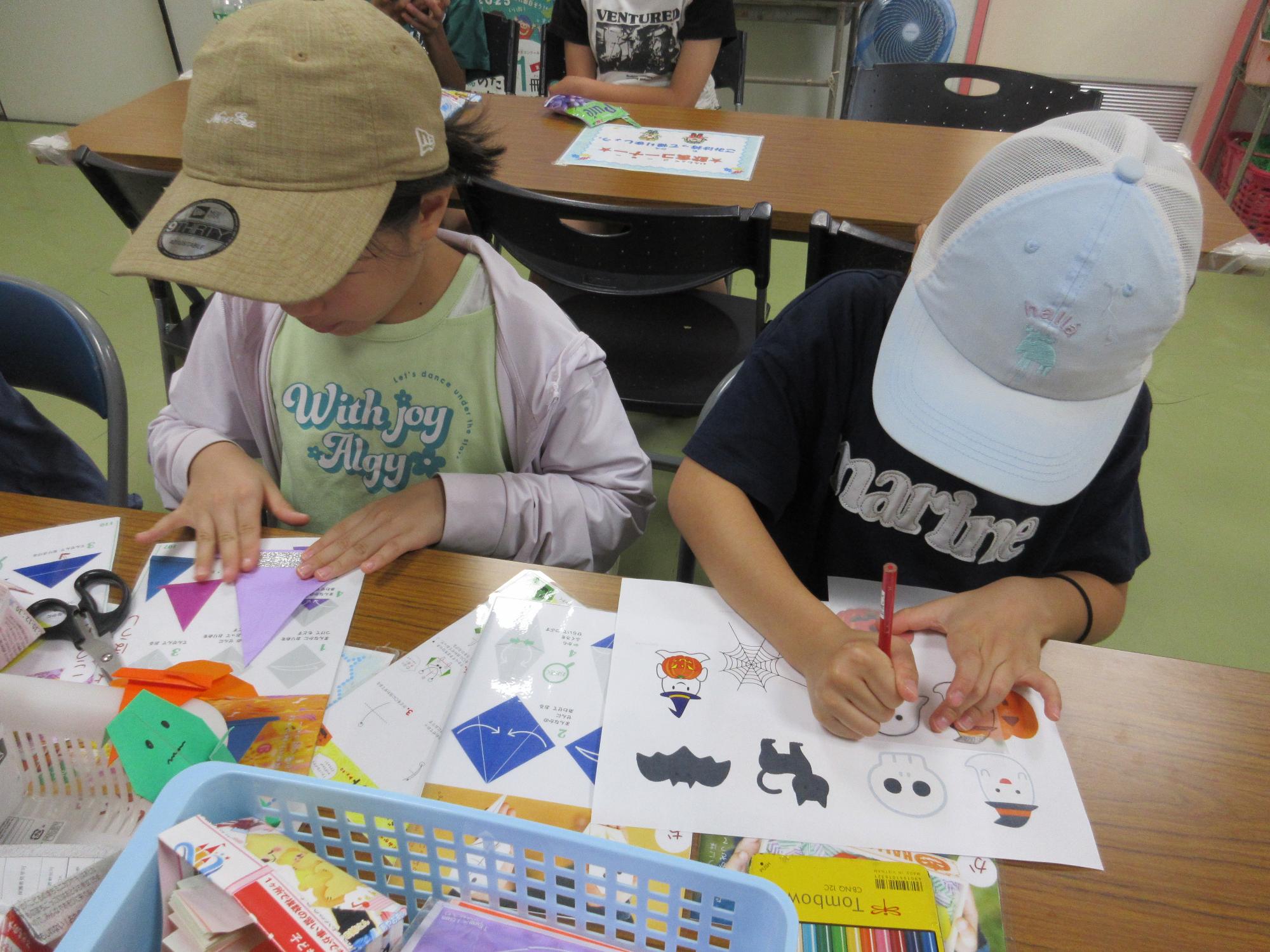 ハロウィンおばけの絵を描く子どもと折り紙で帽子を折る子ども