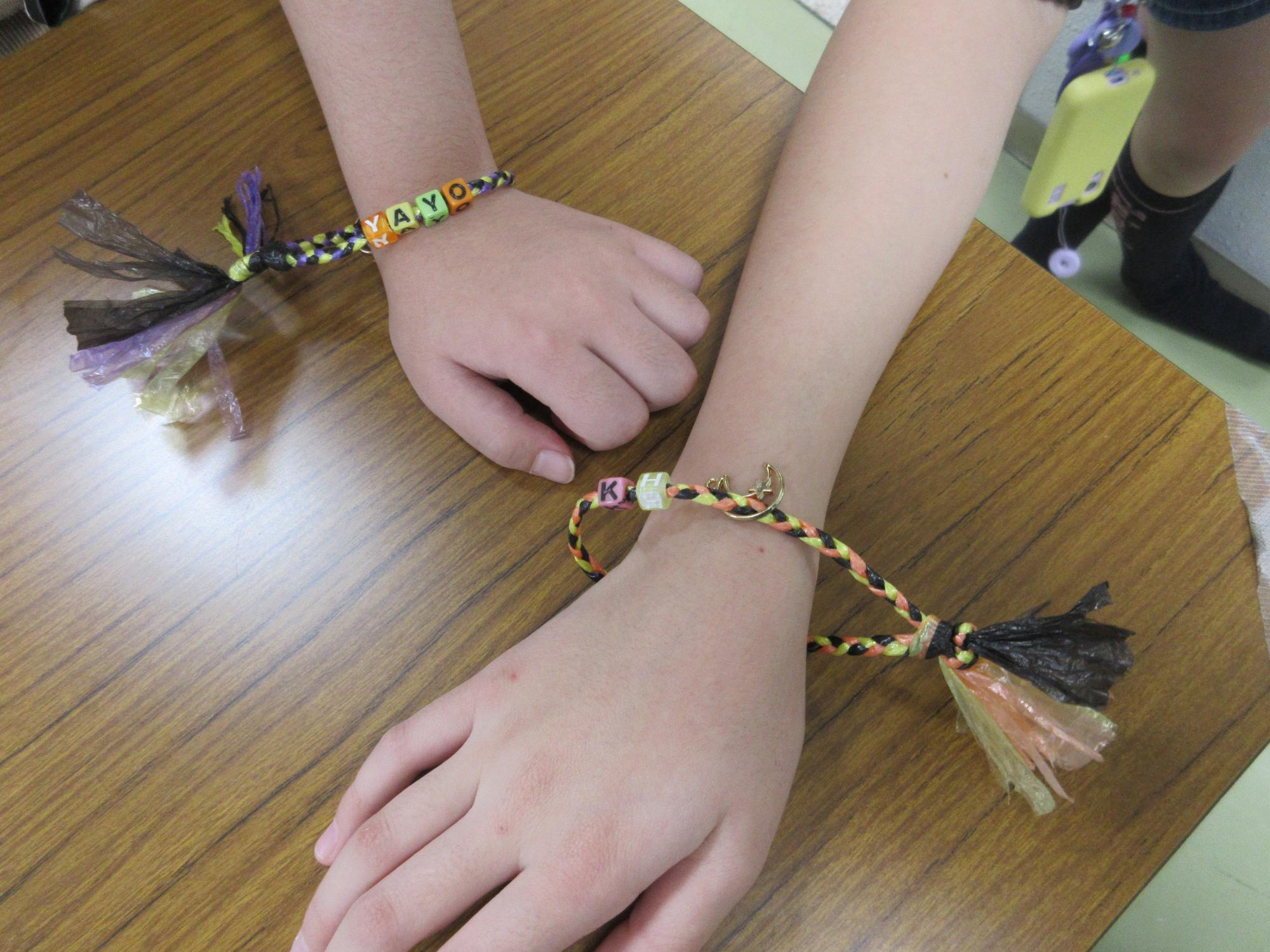 自分で作ったハロウィンカラーのミサンガをつけた子供の手