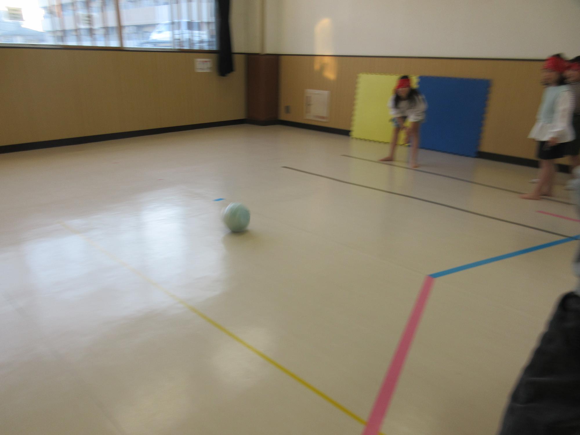 目かくしをしてボールを転がす子ども