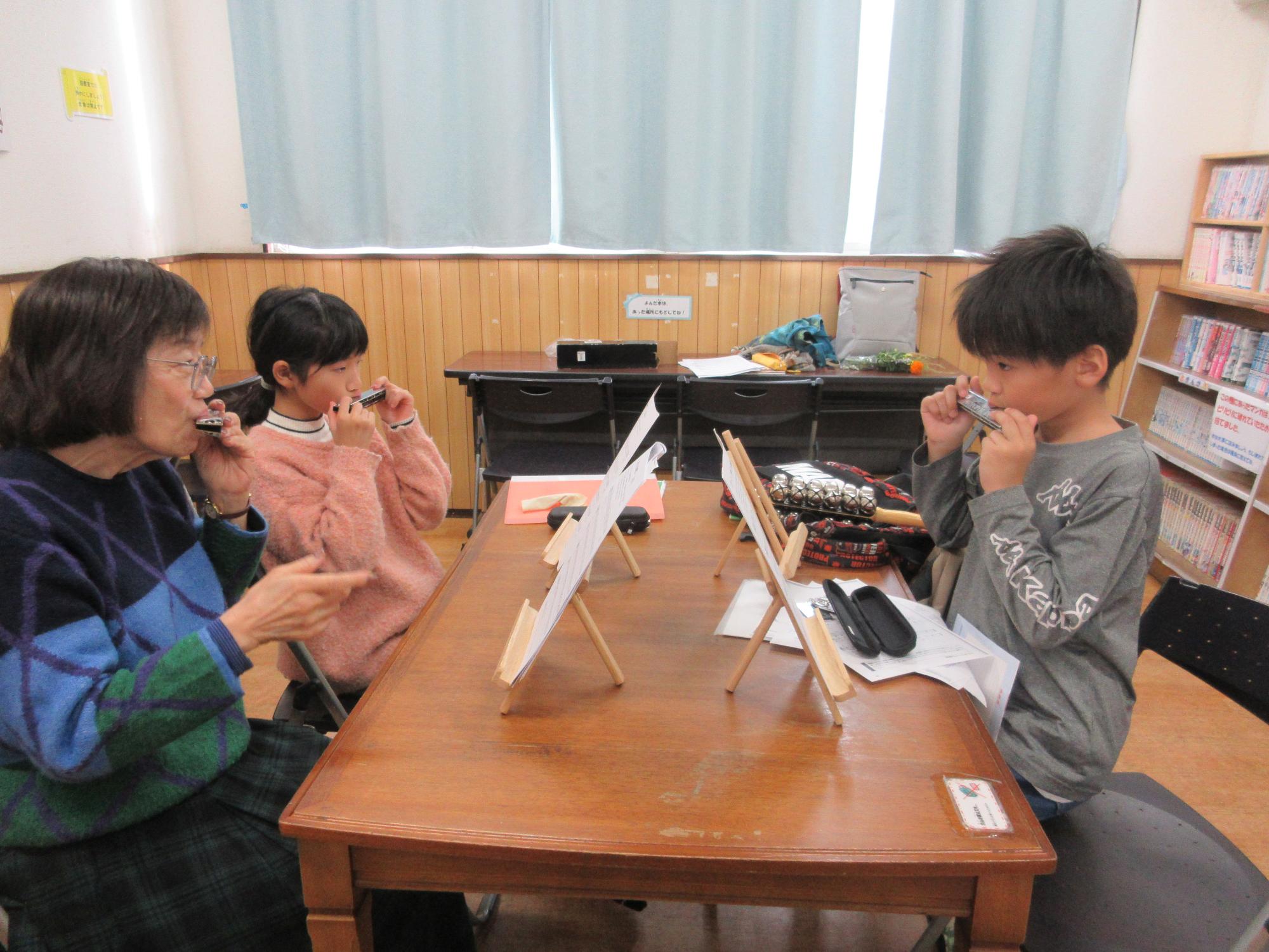 先生の指導を受けハーモニカを吹く子どもたち