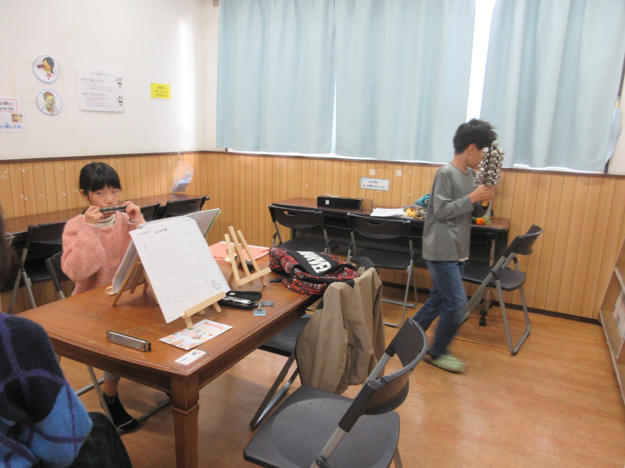 鈴を使ってハーモニカの練習をする子どもたち