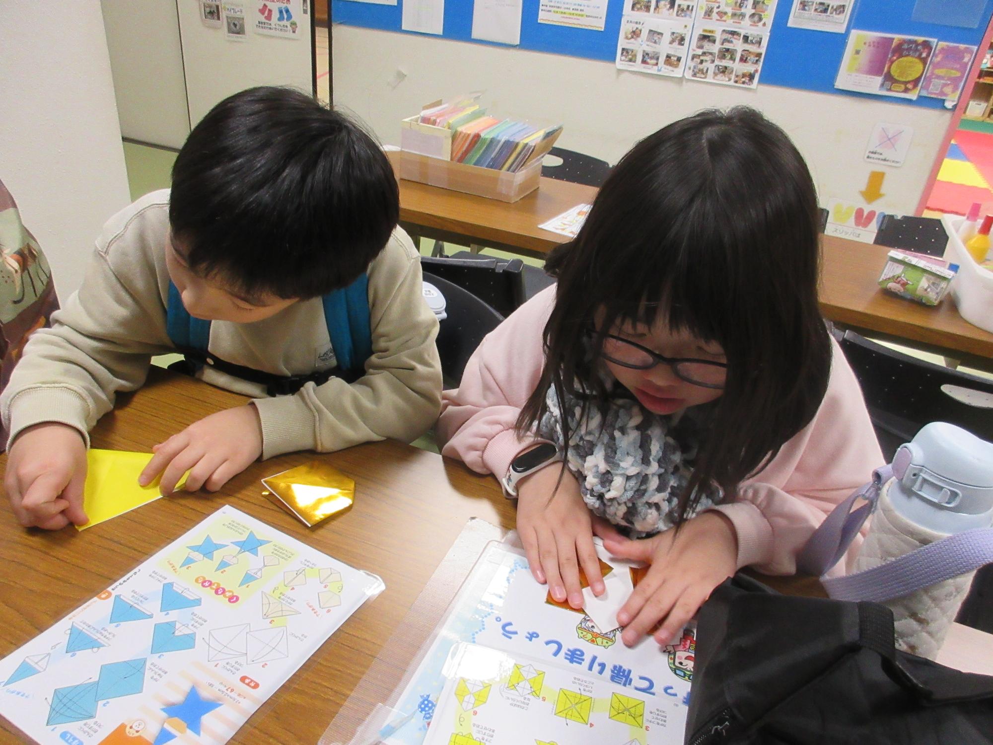 作り方を見ながら折り紙を折る子ども