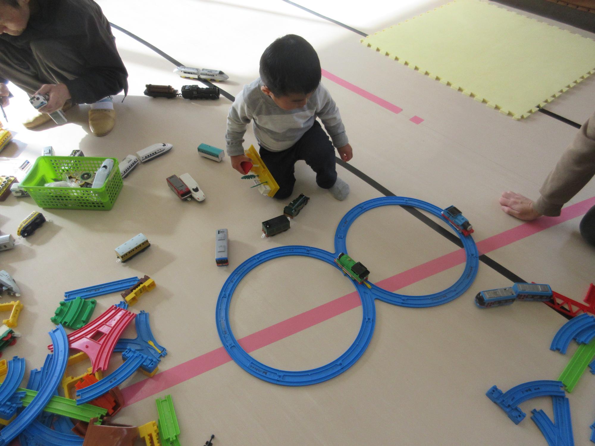 八の字の線路を走る電車をながめる子ども