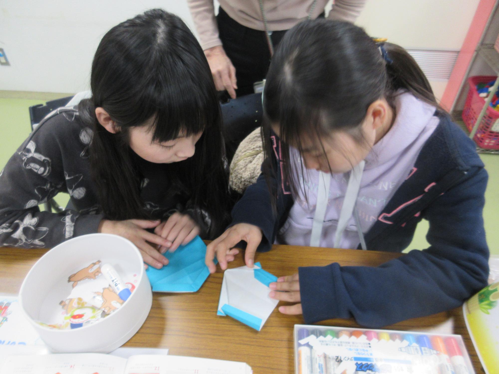 水色の折り紙で絵馬を作る子どもたち