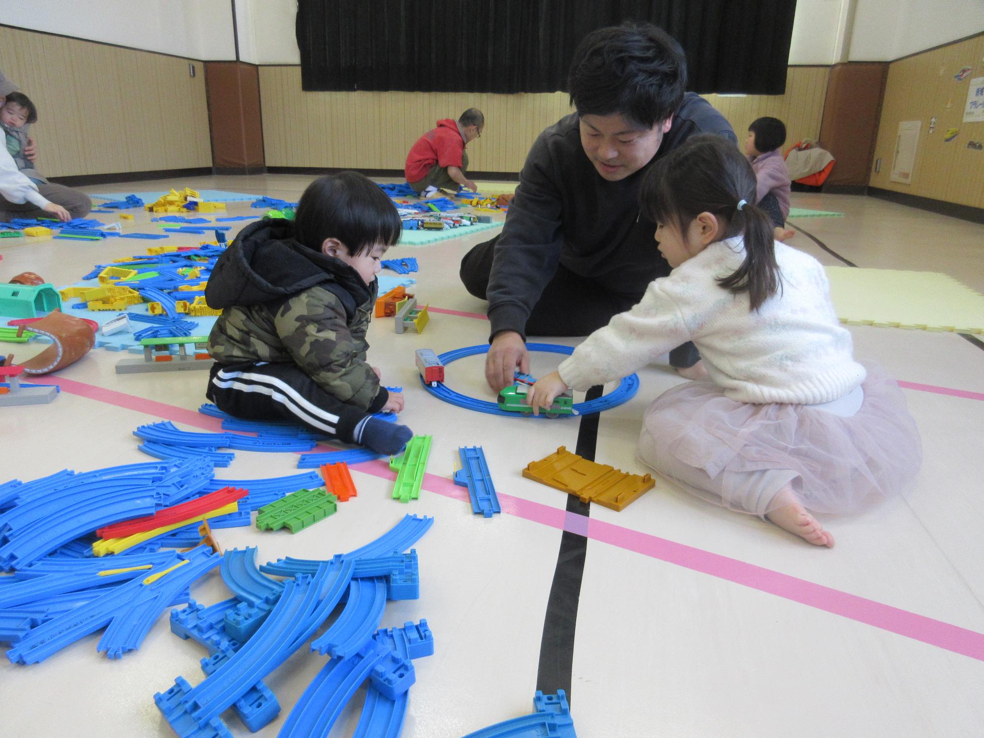 まるい線路に電車を走らせて楽しむ親子