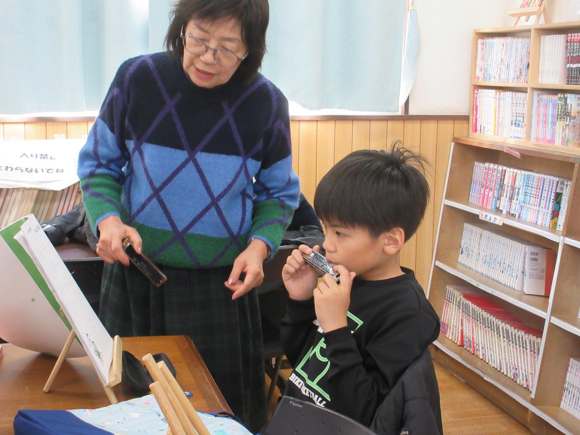 ハーモニカの指導を受けるこども