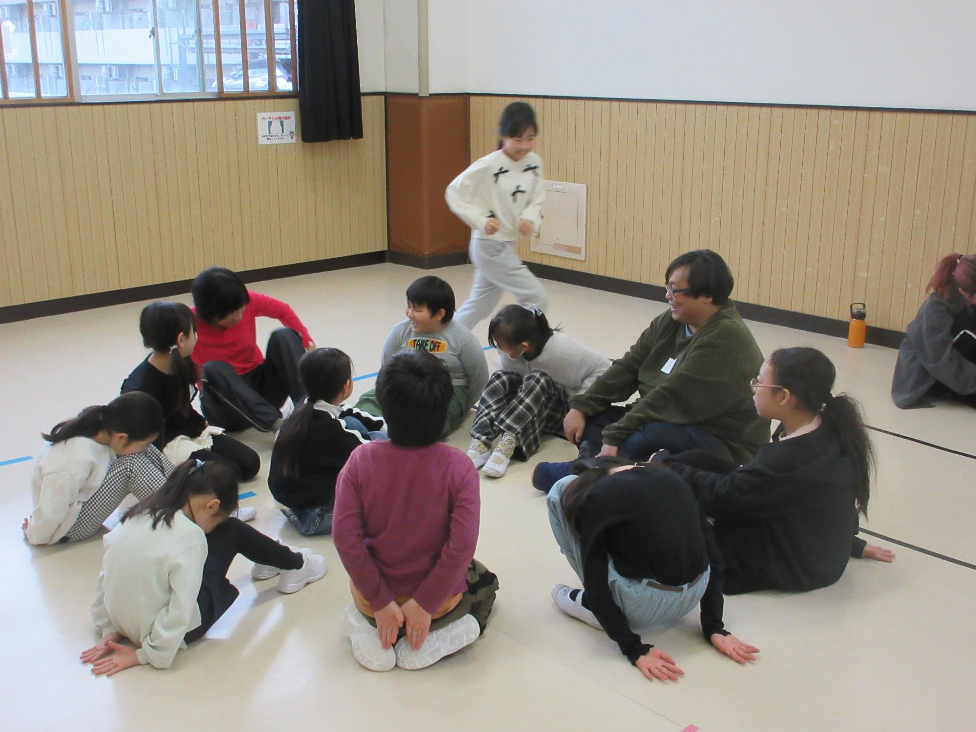 輪になって座り鬼がハンカチを落とすのを待つ子どもたち