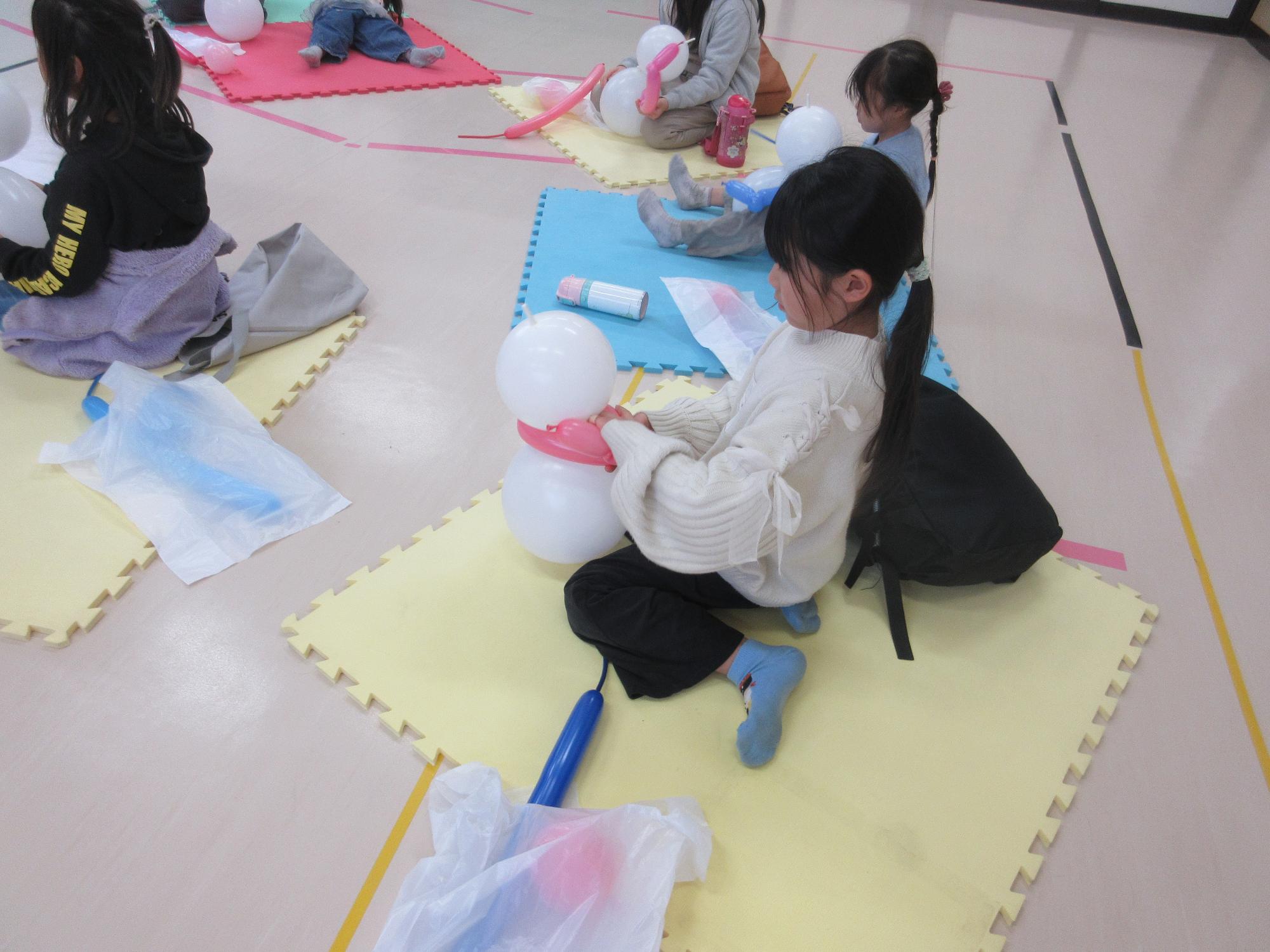 白いだるまの風船に長い風船を巻き付けているところ