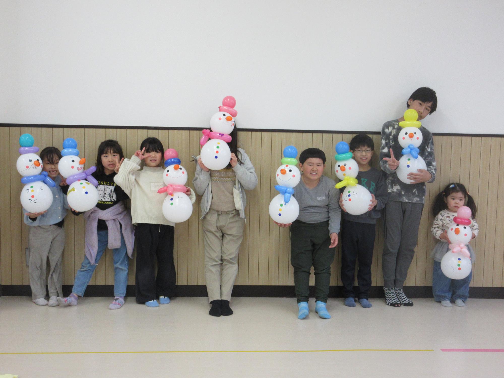 自分で作った風船雪だるまを持って並ぶ子どもたち