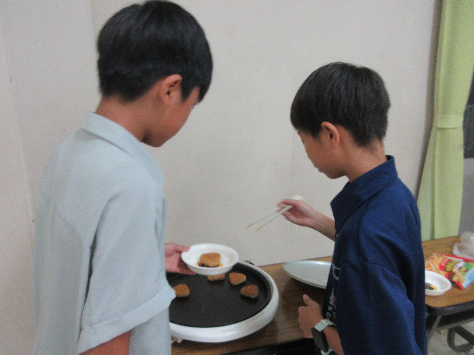 中高生がホットプレートで焼きおにぎりを焼いている様子の写真