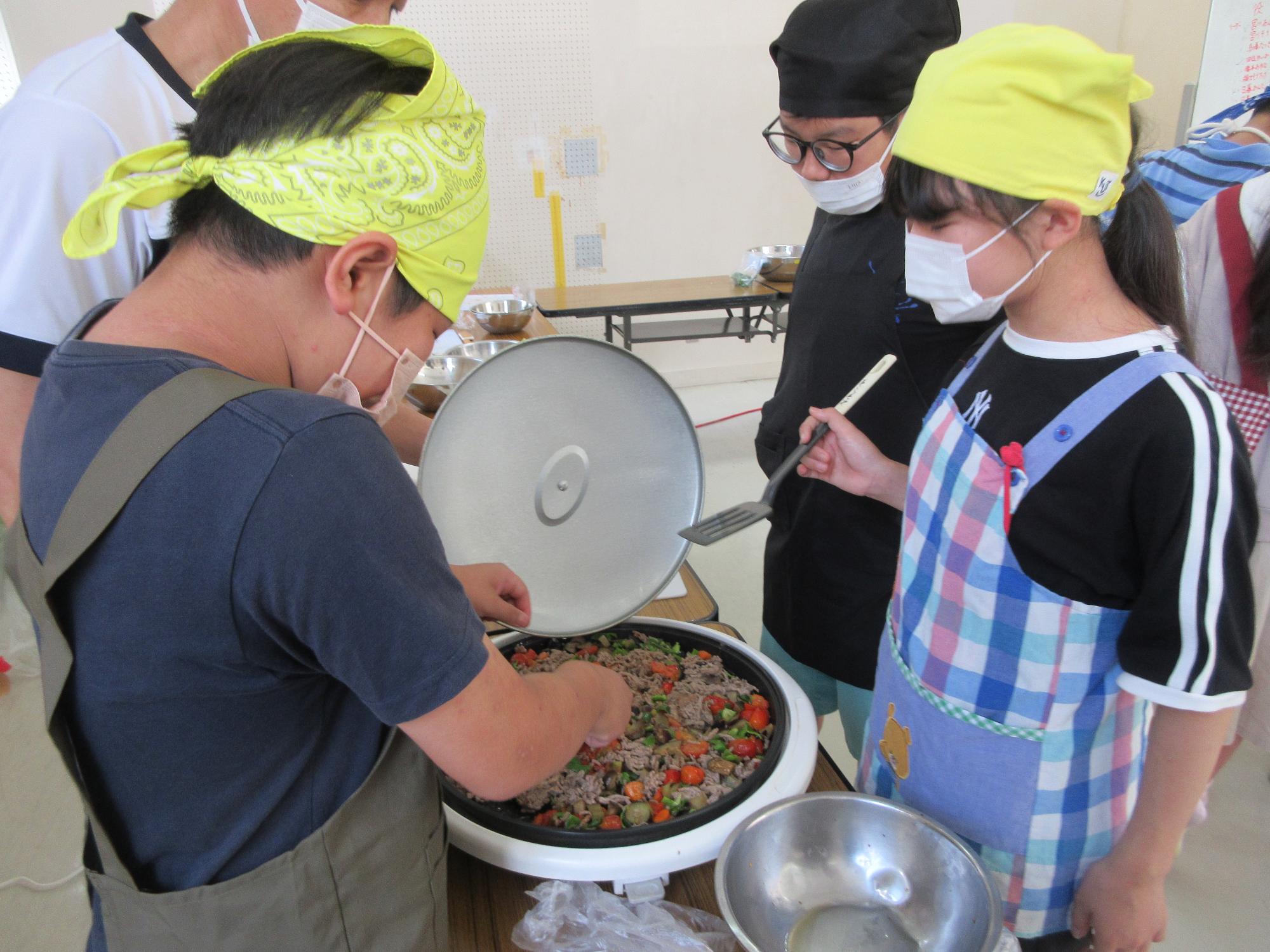 ひき肉と野菜を炒めている子どもたちの様子の写真