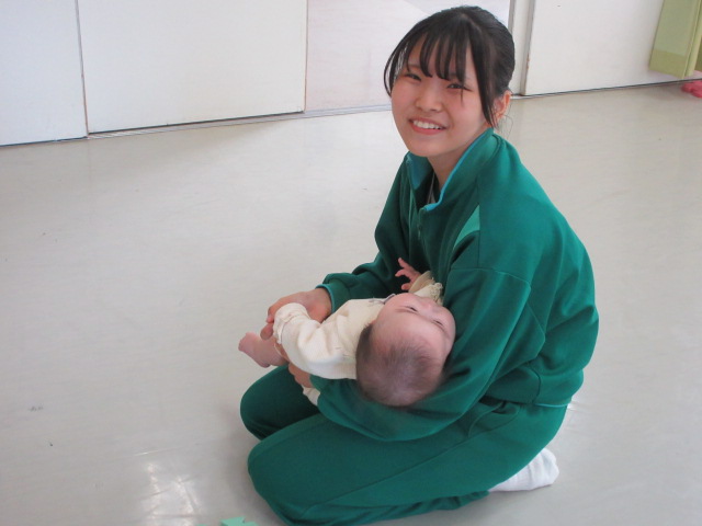 赤ちゃんを抱っこさせてもらっている中学生の様子の写真