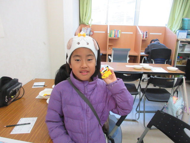 集中して完成させたアイロンビーズ工作を持つ子どもの様子の写真