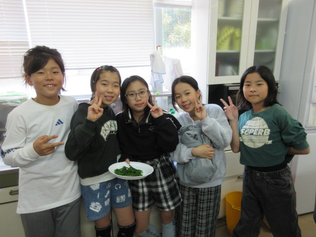 出来上がった茎ブロッコリーを持ってピースサインをする子どもたちの写真