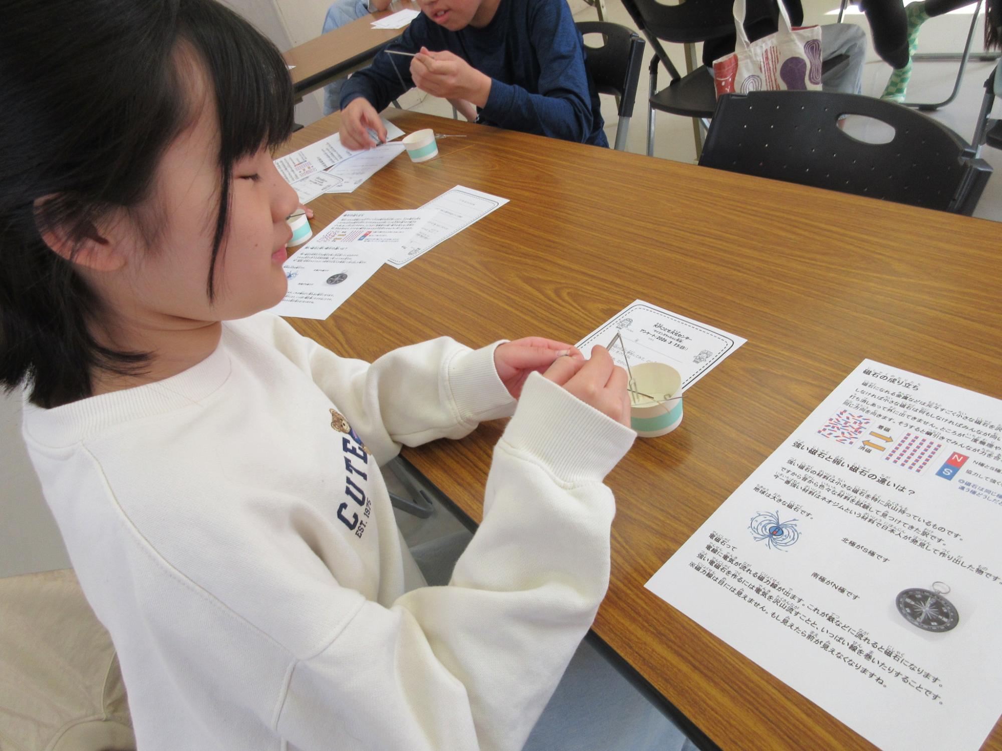 鉄が磁石になる様子を実験を通して見ている子どもたちの様子の写真