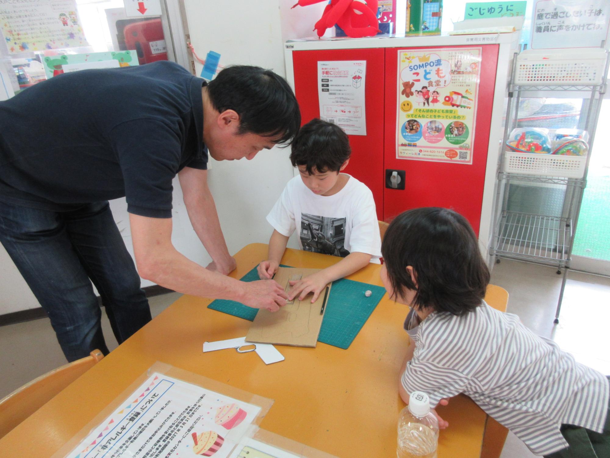 ダンボール銃を作りたいと館長に教わっている小学生の様子の写真