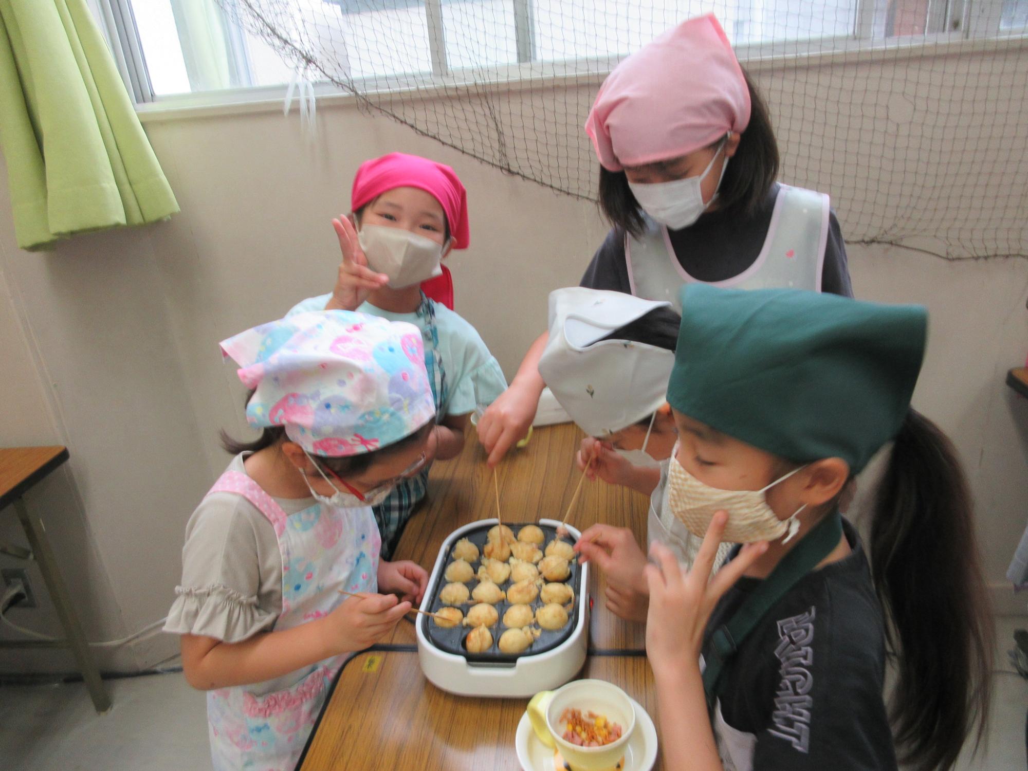 苦戦しながらもたこ焼きをひっくり返せるようになっている小学生の様子の写真