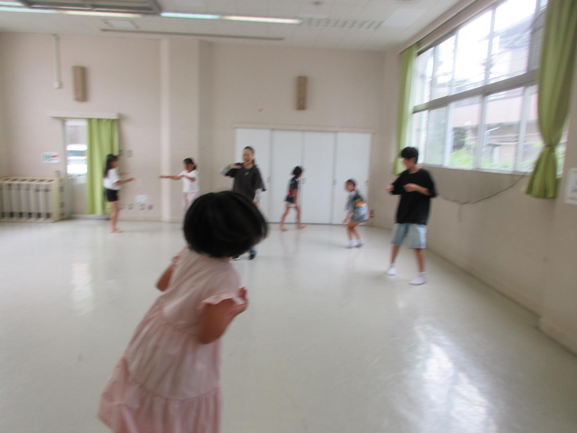 自分の手の甲に乗せたペットボトルキャップを守りながら周りの人のキャップを落とす子どもたちの様子の写真