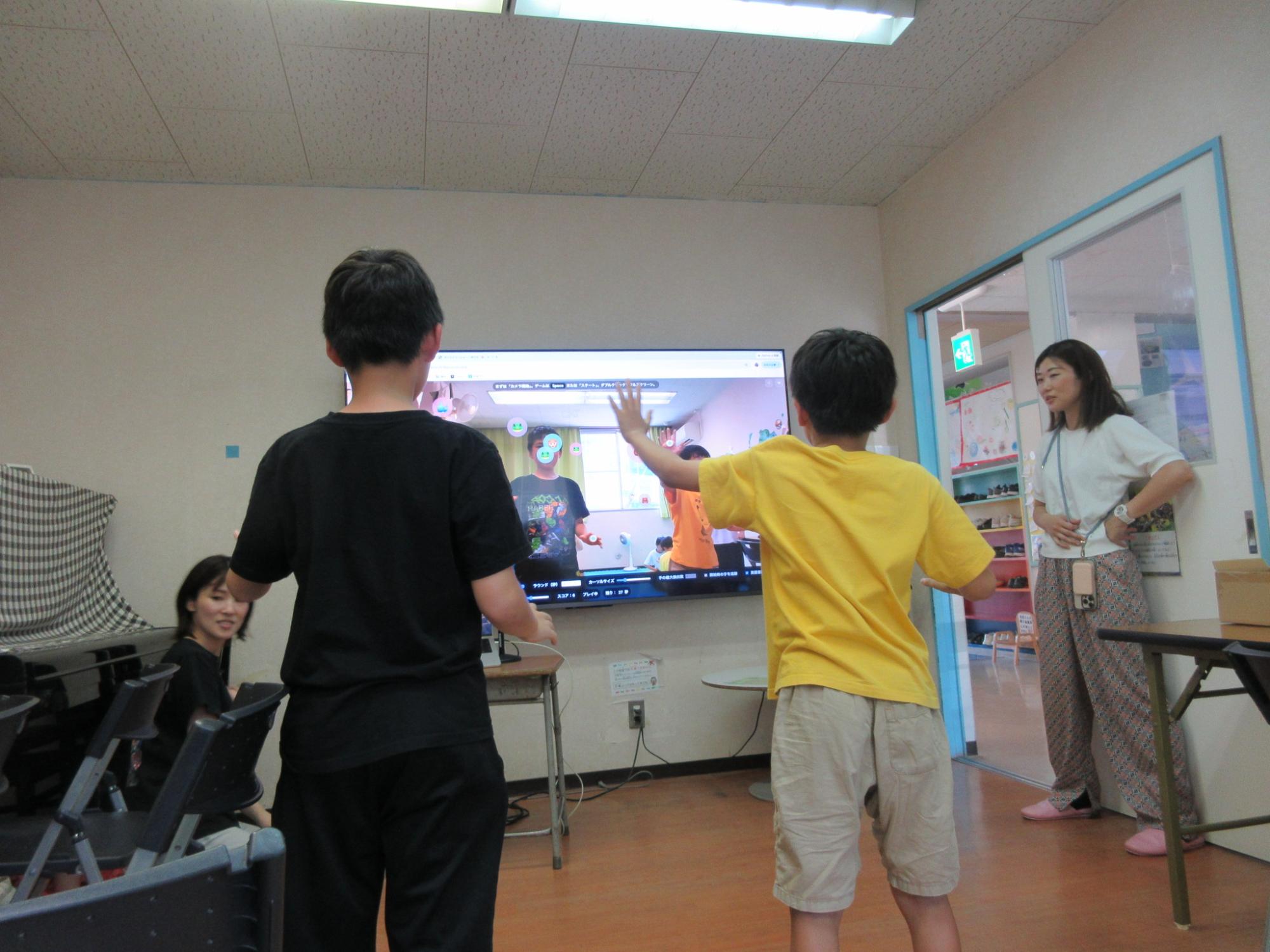 二人でテレビに投影された動物の絵にタッチして点数を稼ぐゲームをして遊ぶ様子