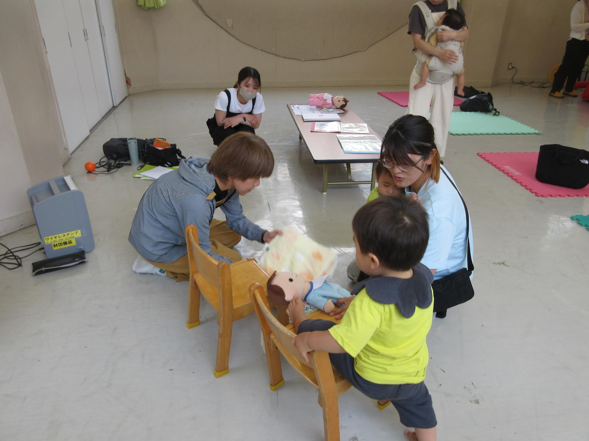 こどもが食事をするイスの調整をバスタオルや雑誌でする方法を学ぶ親子の様子の写真