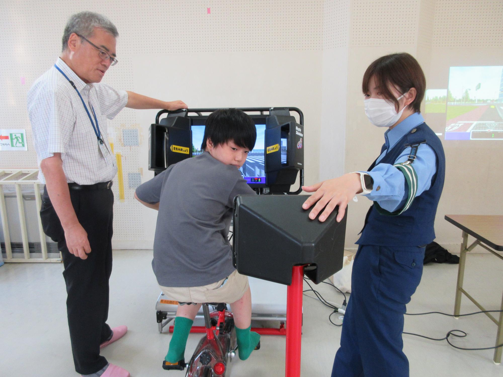 自転車シミュレーターで、後方確認の仕方を学ぶ子どもの様子の写真