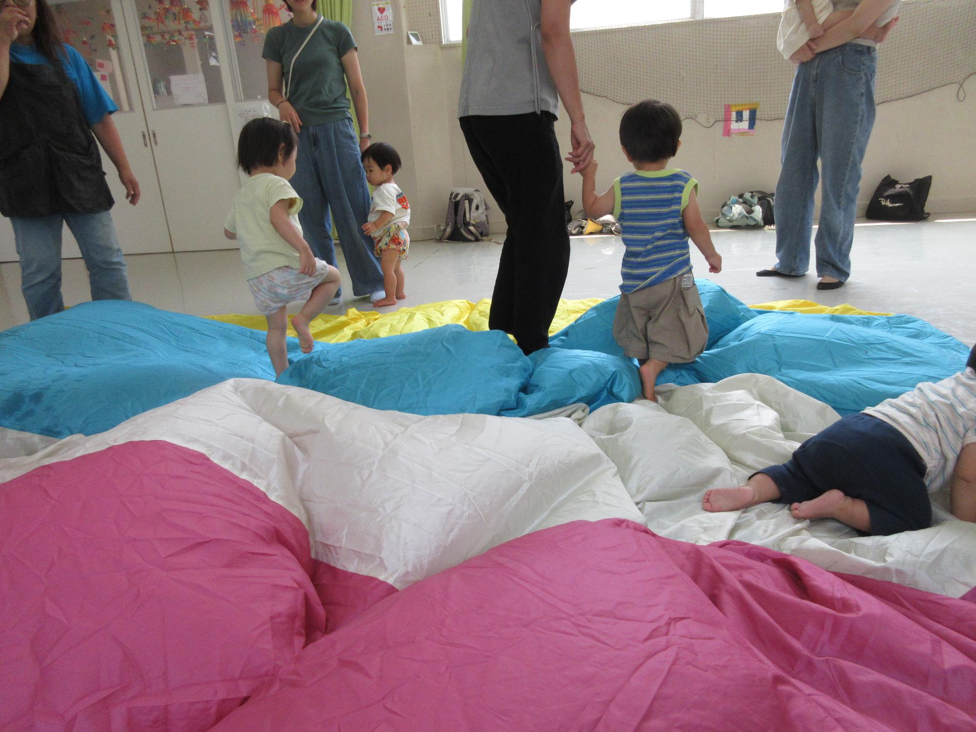 パラバルーンを膨らませて、子どもたちが中にもぐったり、乗ったりしている様子の写真