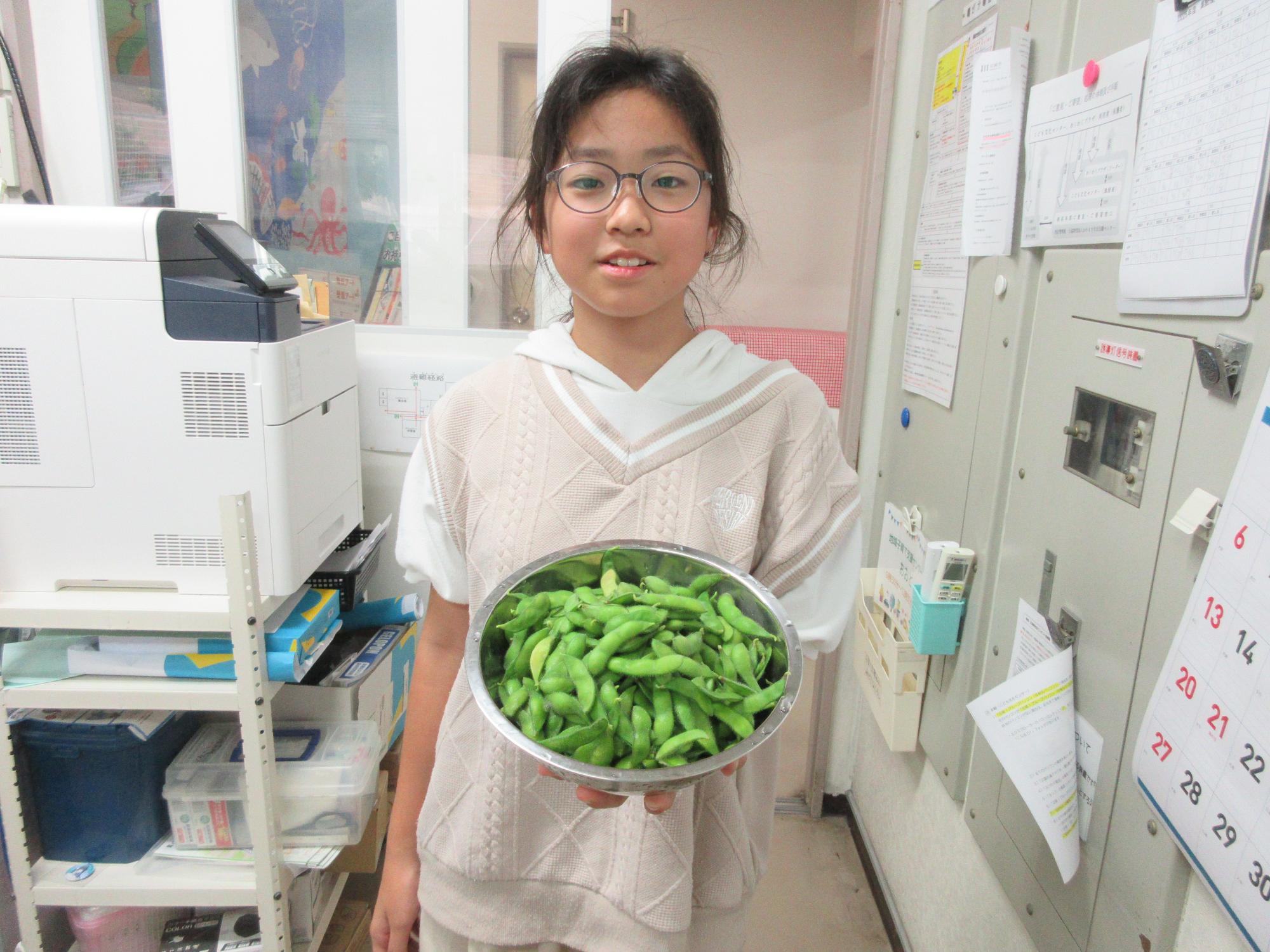 どっさり収穫ができた枝豆を持つ子どもの様子の写真