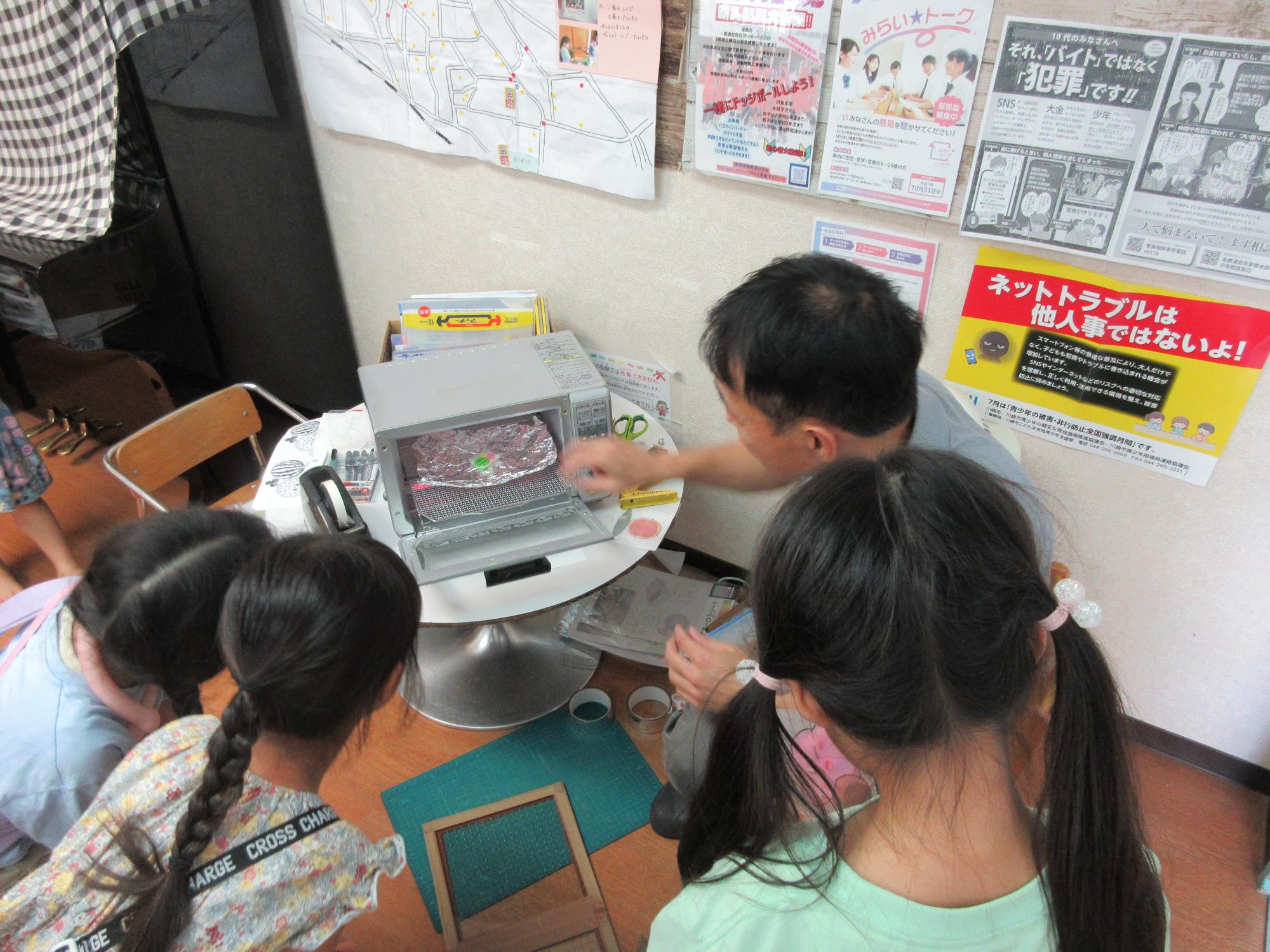 プラバンが焼きあがる様子と見学している子どもたちの様子の写真