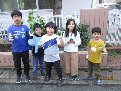 収穫したピーマンと一緒にポーズをとっているクラブ員の写真