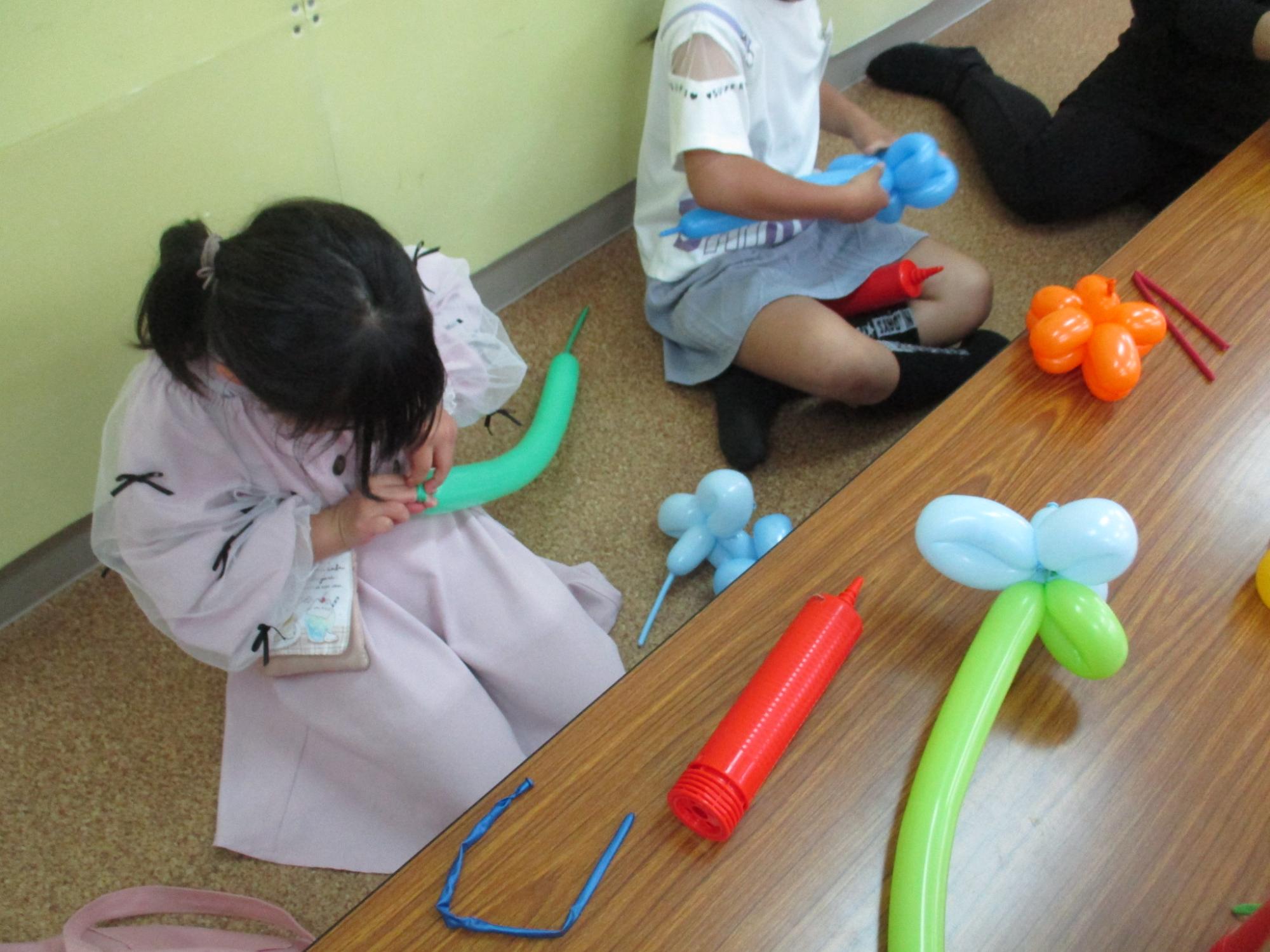 子どもたちが色とりどりの風船を使ってバルーンアートを作成している写真