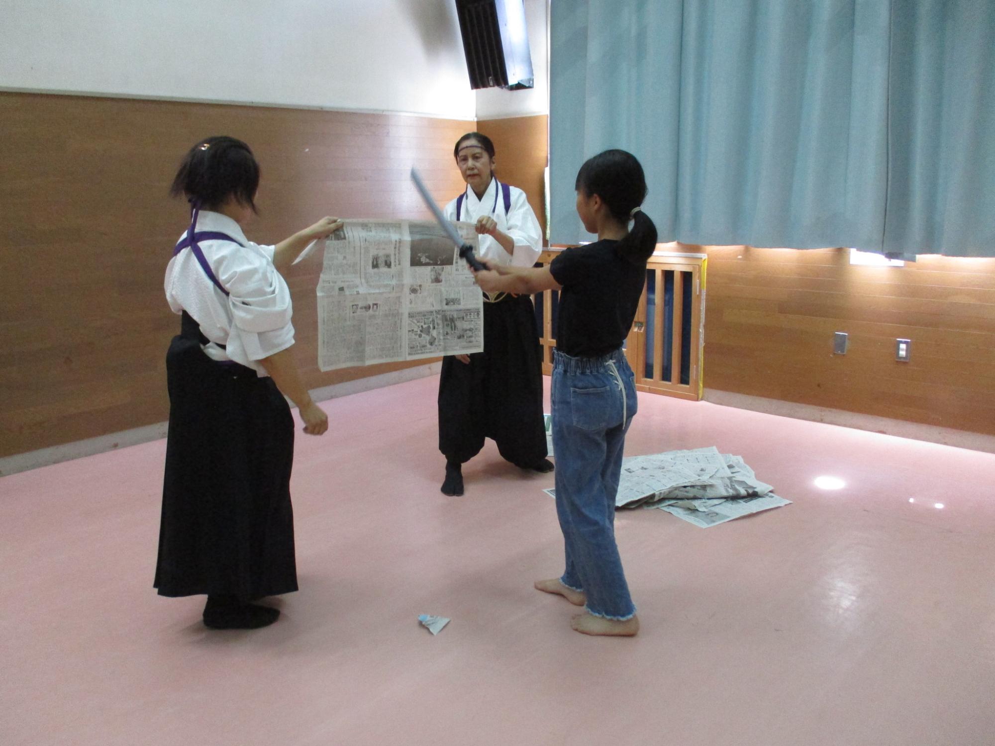 刀で新聞紙を切る様子
