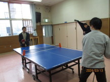 卓球台を挟んでラケットを持った2名の男の子が立ち試合を行っている写真