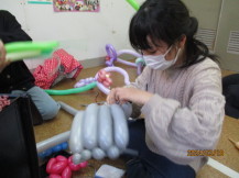 グレー色の風船でバルーンアートの作品を作っている女の子の写真