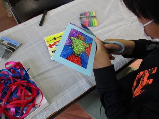 貼った絵のはみ出た部分を切っている写真