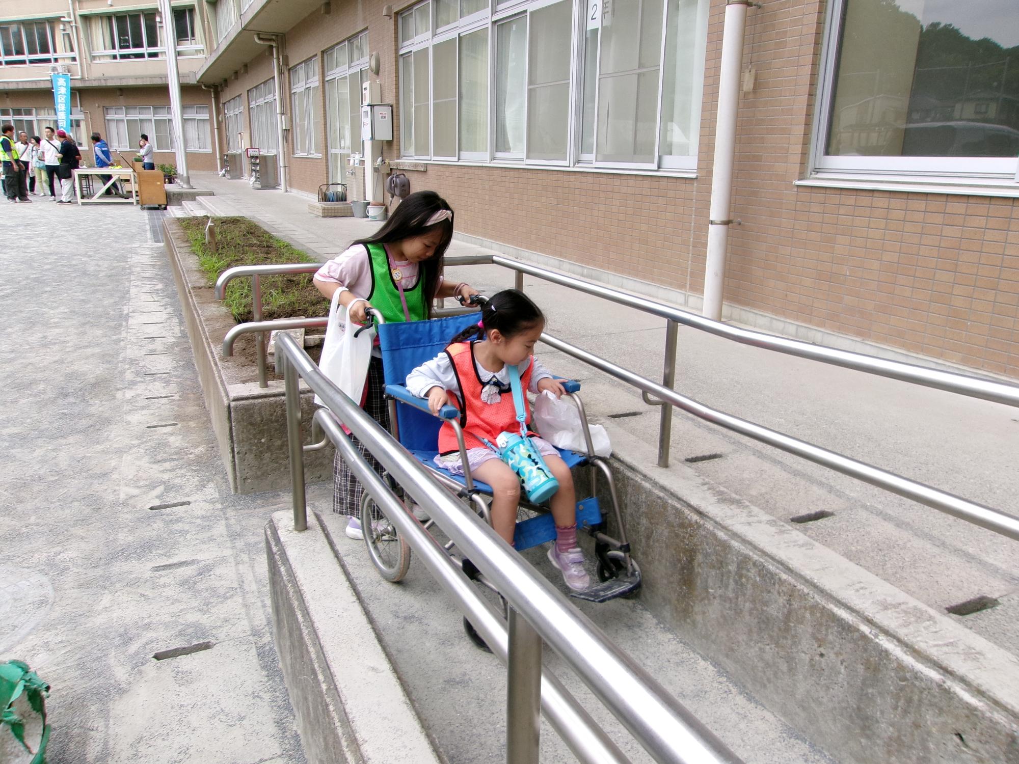 防災教室で車いす体験をしている子どもの写真