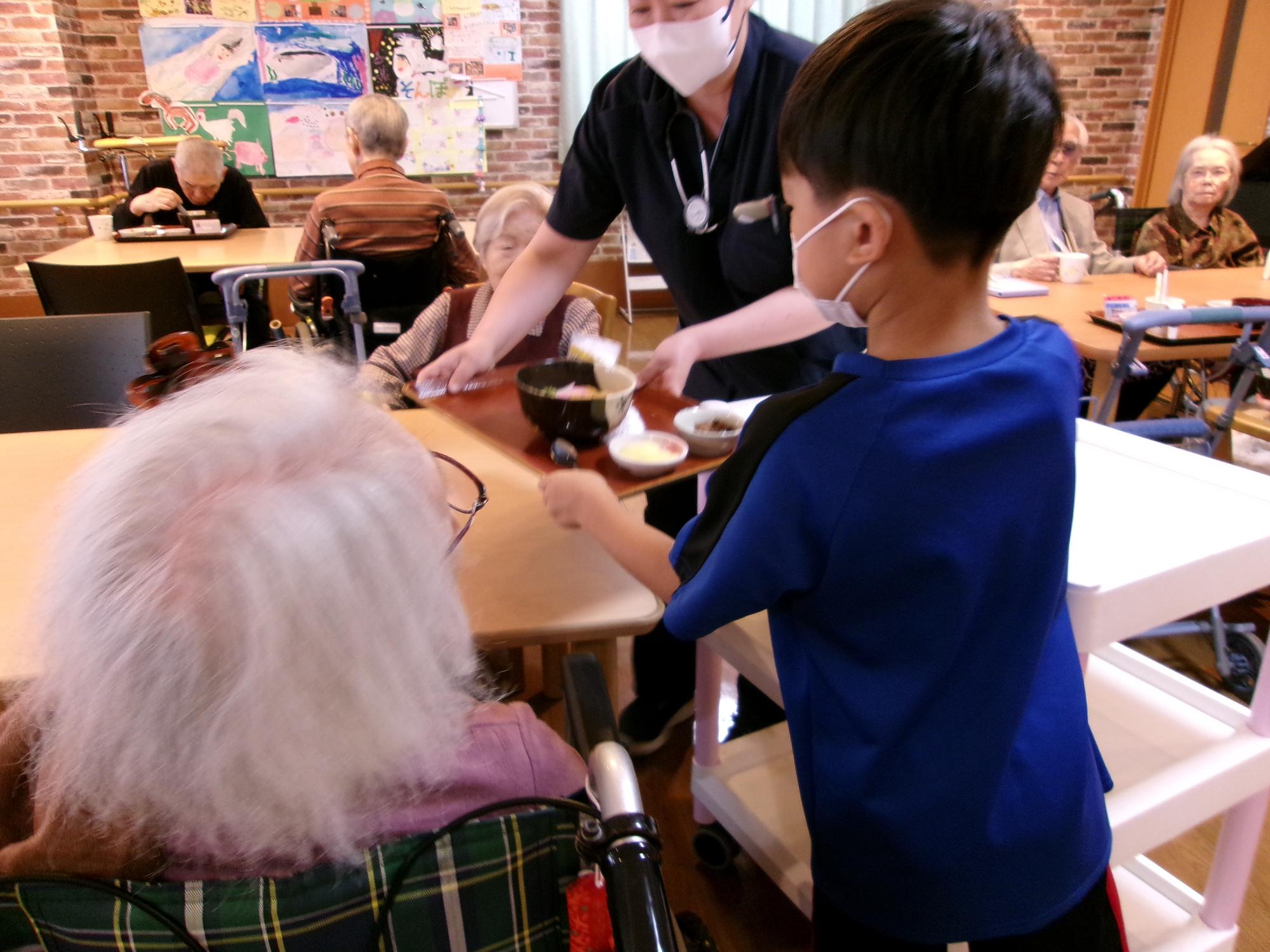入居者のおばあちゃんに昼食の配膳お手伝いをしている写真