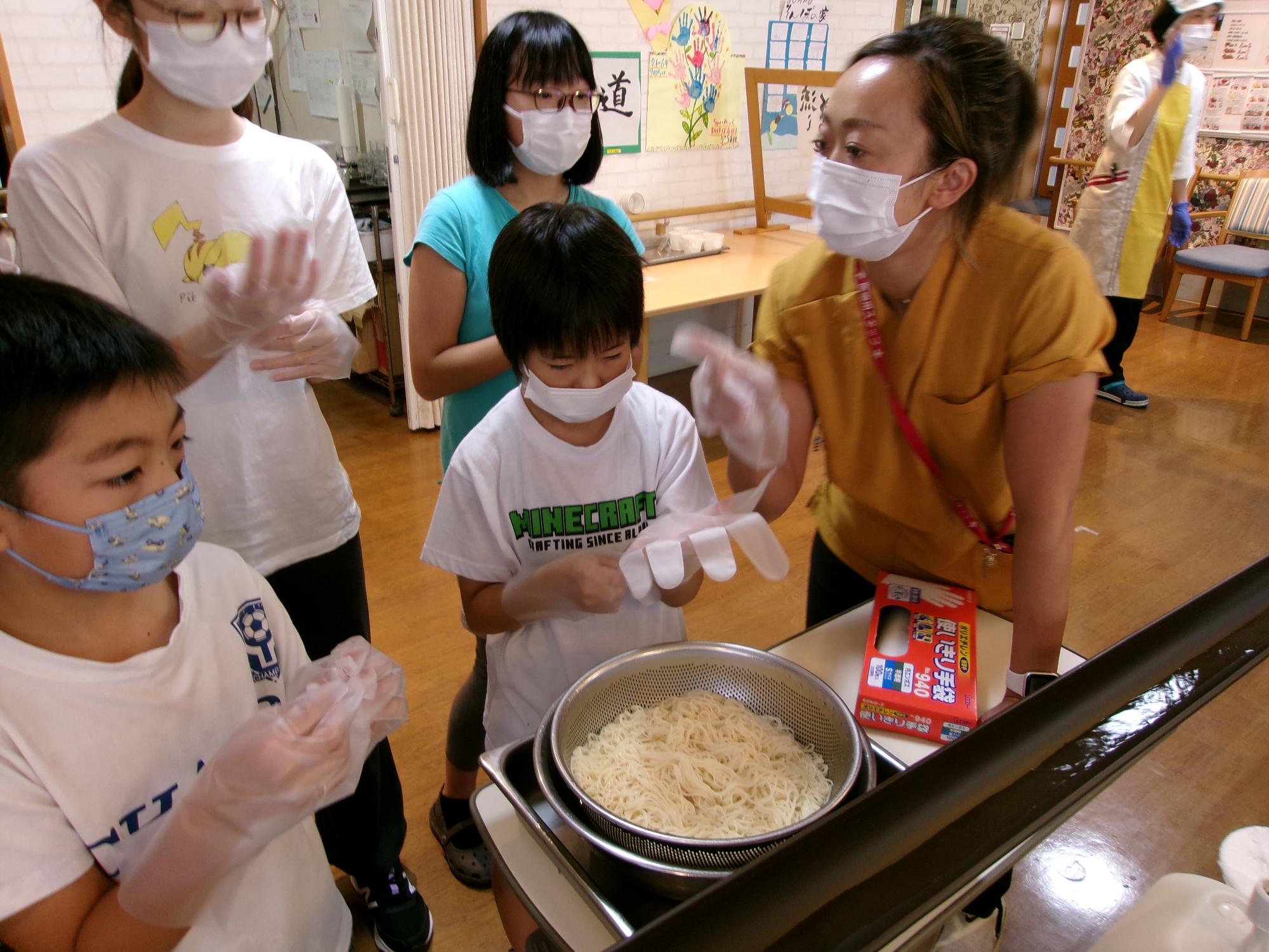 子どもたちが流しそうめんの手伝いをするため説明を受けている写真