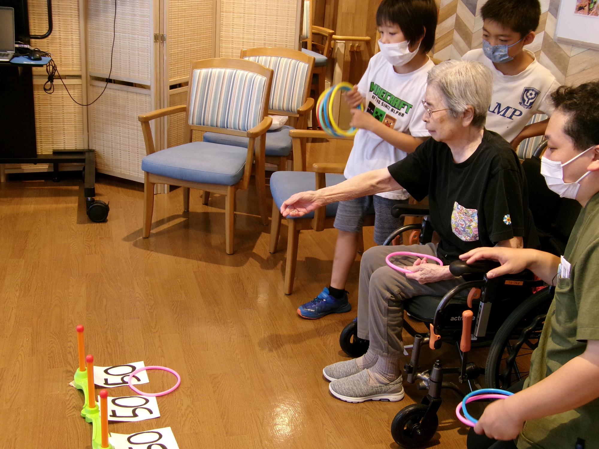 子どもたちが輪投げコーナーの手伝いをしている写真