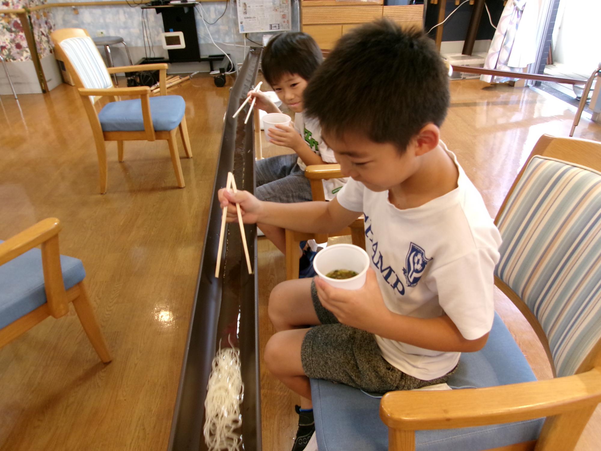 子どもたちが流しそうめんをしている写真