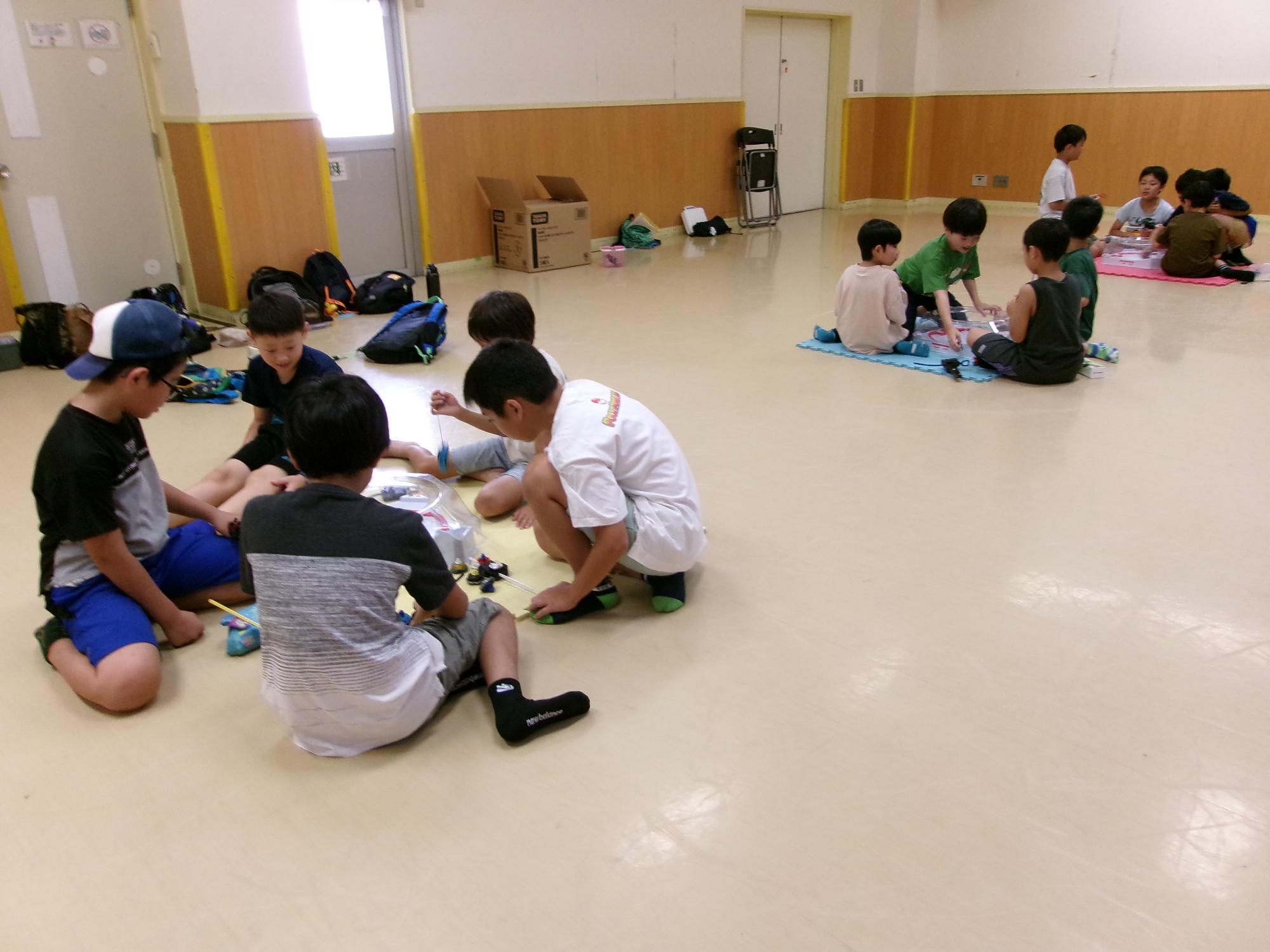 子どもたちが集会室でベイブレードを行っている写真