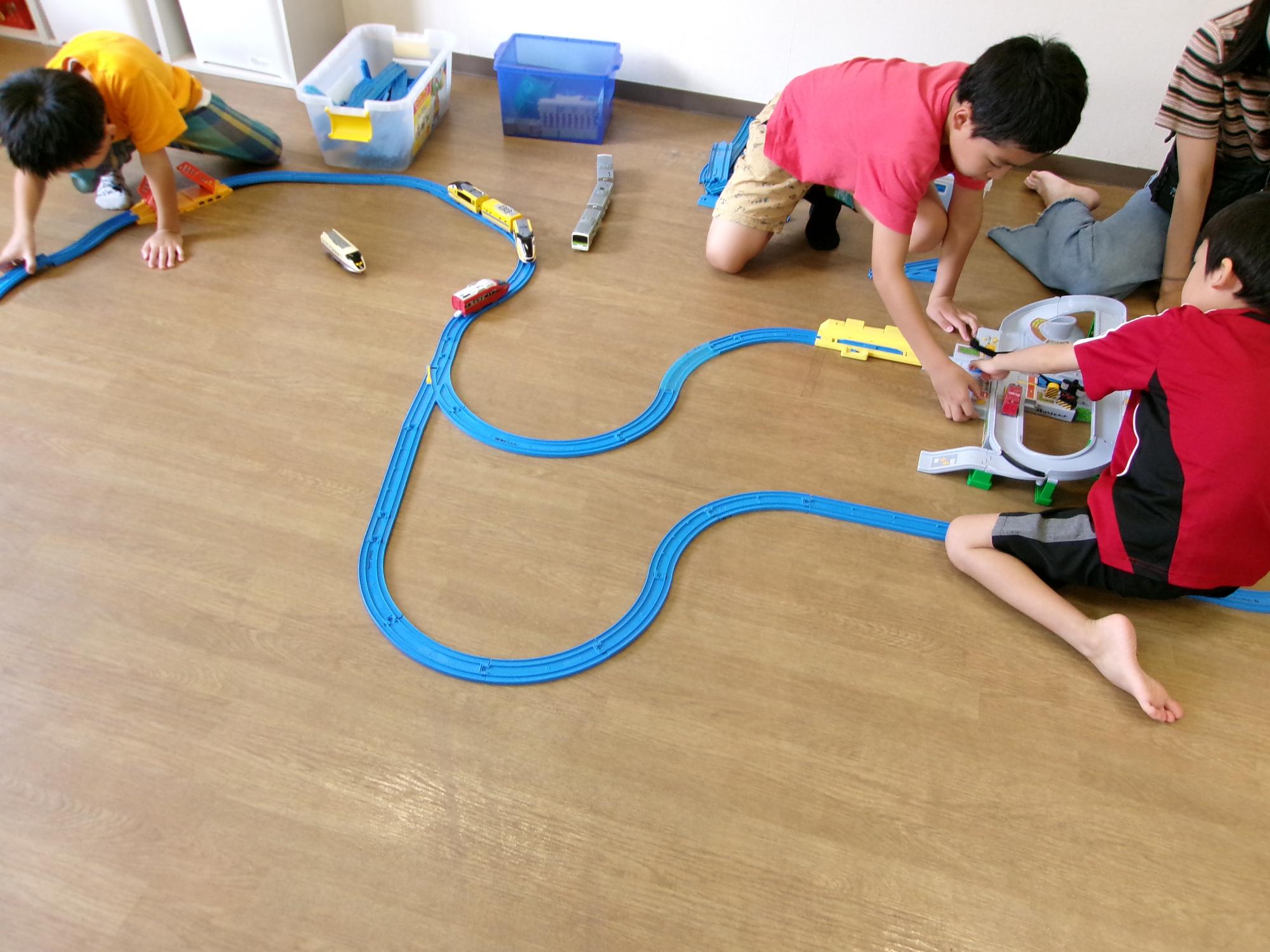 プラレールを一生懸命繋げている子どもたちの写真