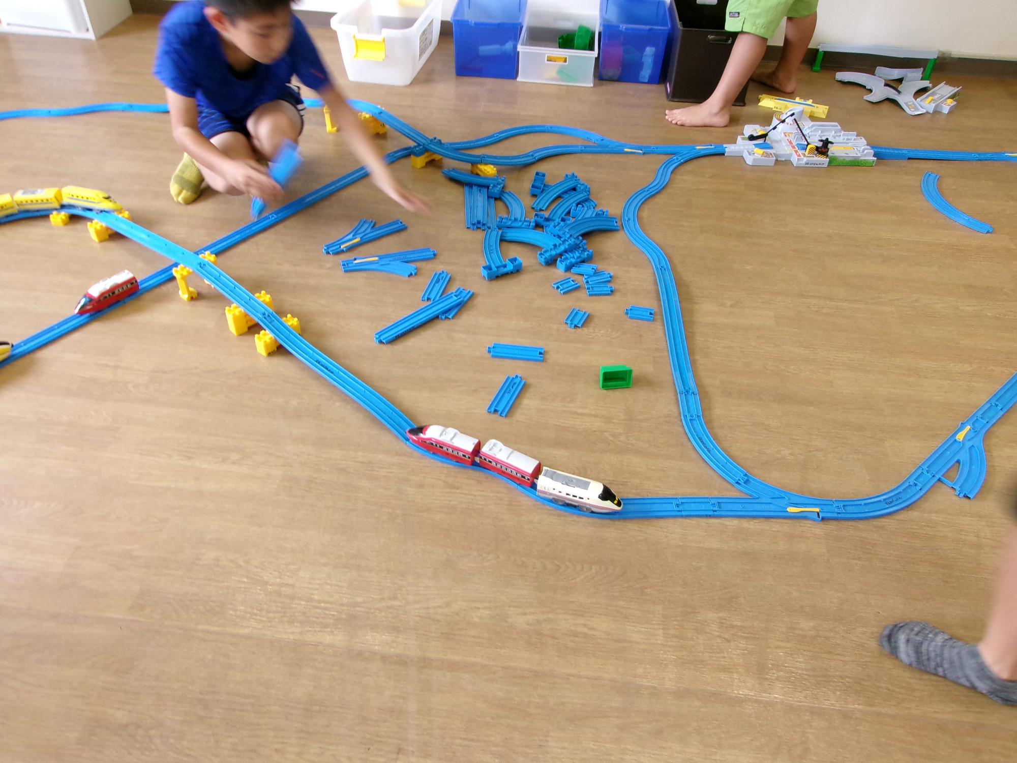 立体化、複線化した線路で電車を履いsらせている子どもたちの写真
