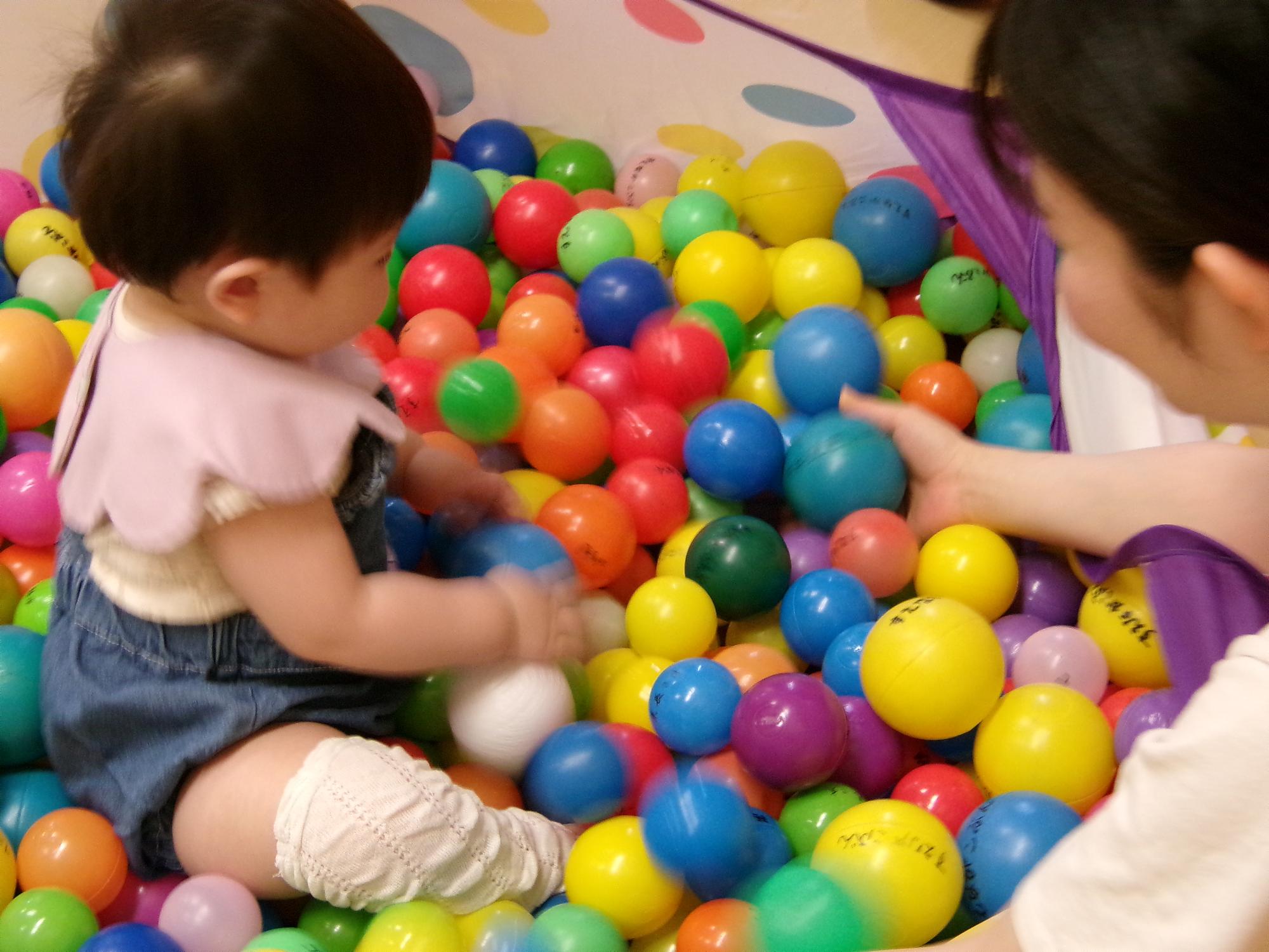 ボールプールで笑顔で遊ぶ幼児の写真