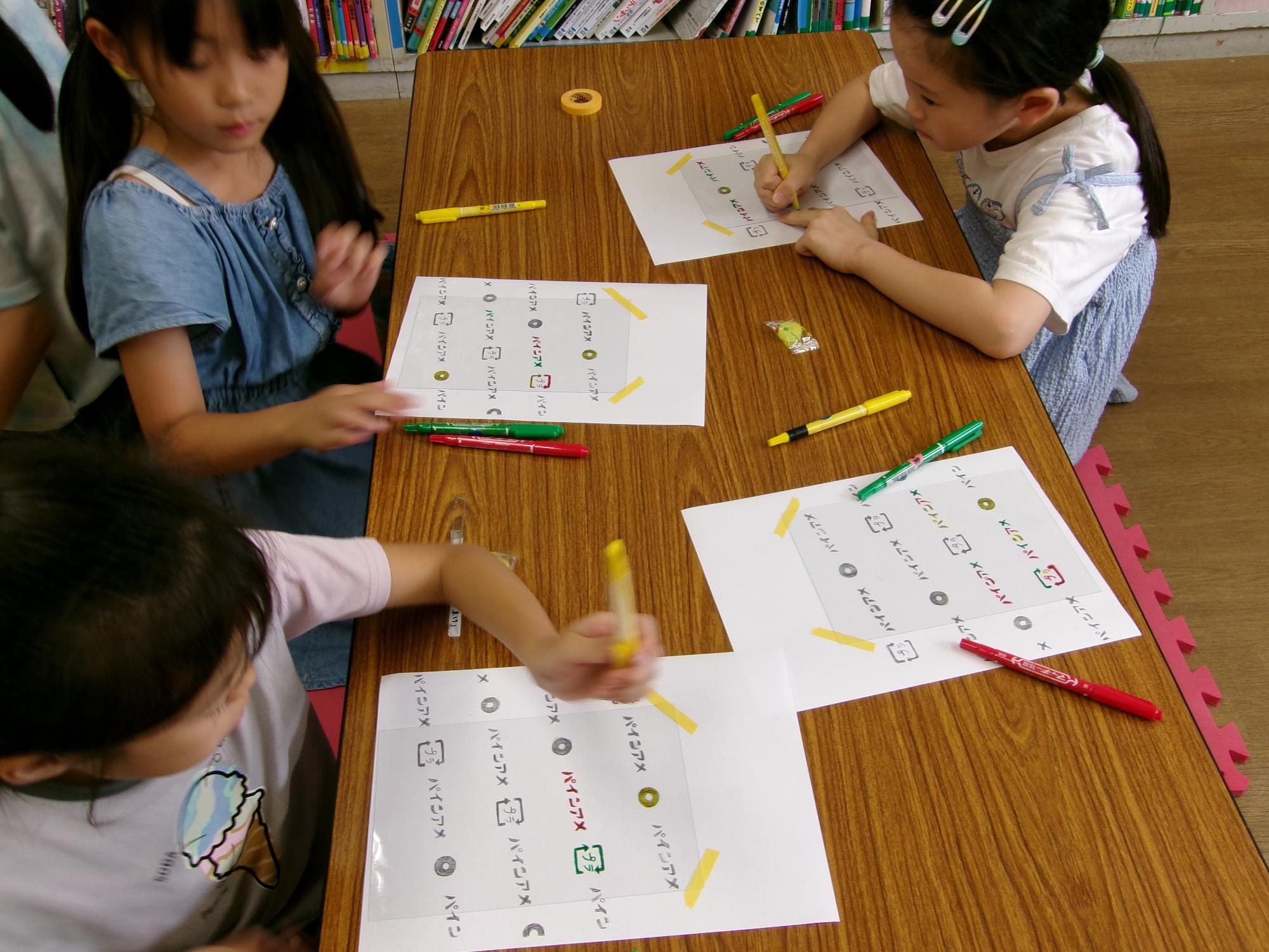 子どもたちがパインアメの袋の柄を描いている写真