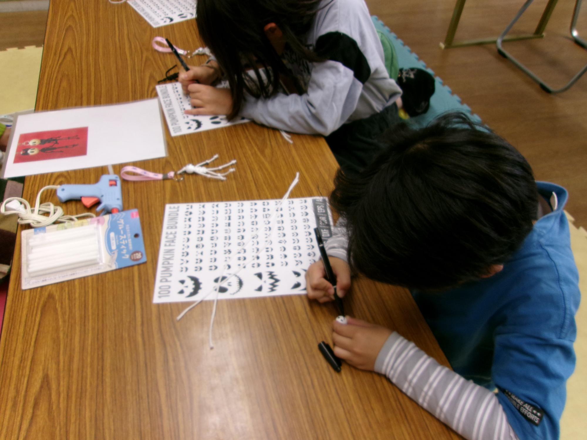 子どもたちがウッドビーズに顔を描いている写真